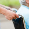 Wheelchair Elderly woman in wheelchair pushed by nurse's hands.