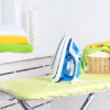 Iron and clothes on ironing board on interior background Iron and clothes on ironing board on interior background